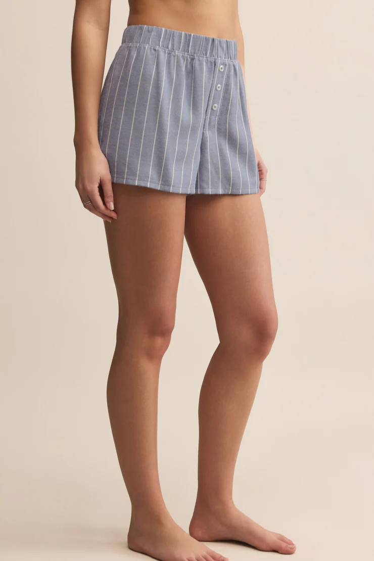 Blue striped shorts worn by a person on a beige background