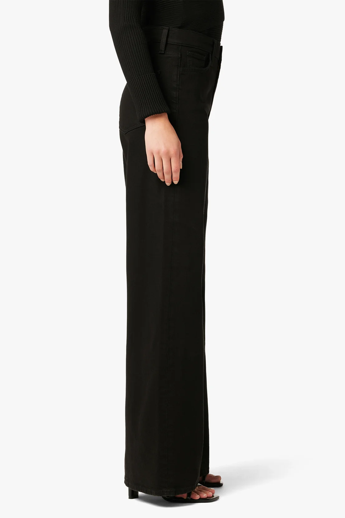 Person wearing black wide-leg pants on a white background