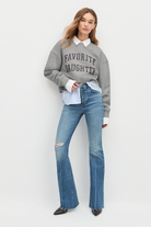 Woman wearing a gray sweater with text and blue jeans on a white background