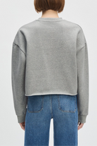 Person wearing a gray sweatshirt and blue jeans on a white background