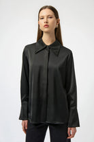 Woman wearing a black blouse with a high collar on a white background