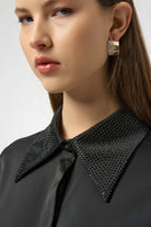 Close-up of a woman wearing a black studded collar with a neutral background