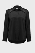 Black blouse with embellished collar on a white background
