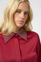 Woman wearing a red blouse with a patterned collar against a white background