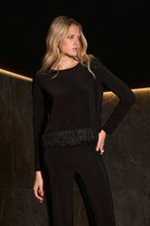 Woman wearing a black outfit with a textured waistband against a dark background
