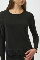 Black long-sleeve top with fringe detail on a white background