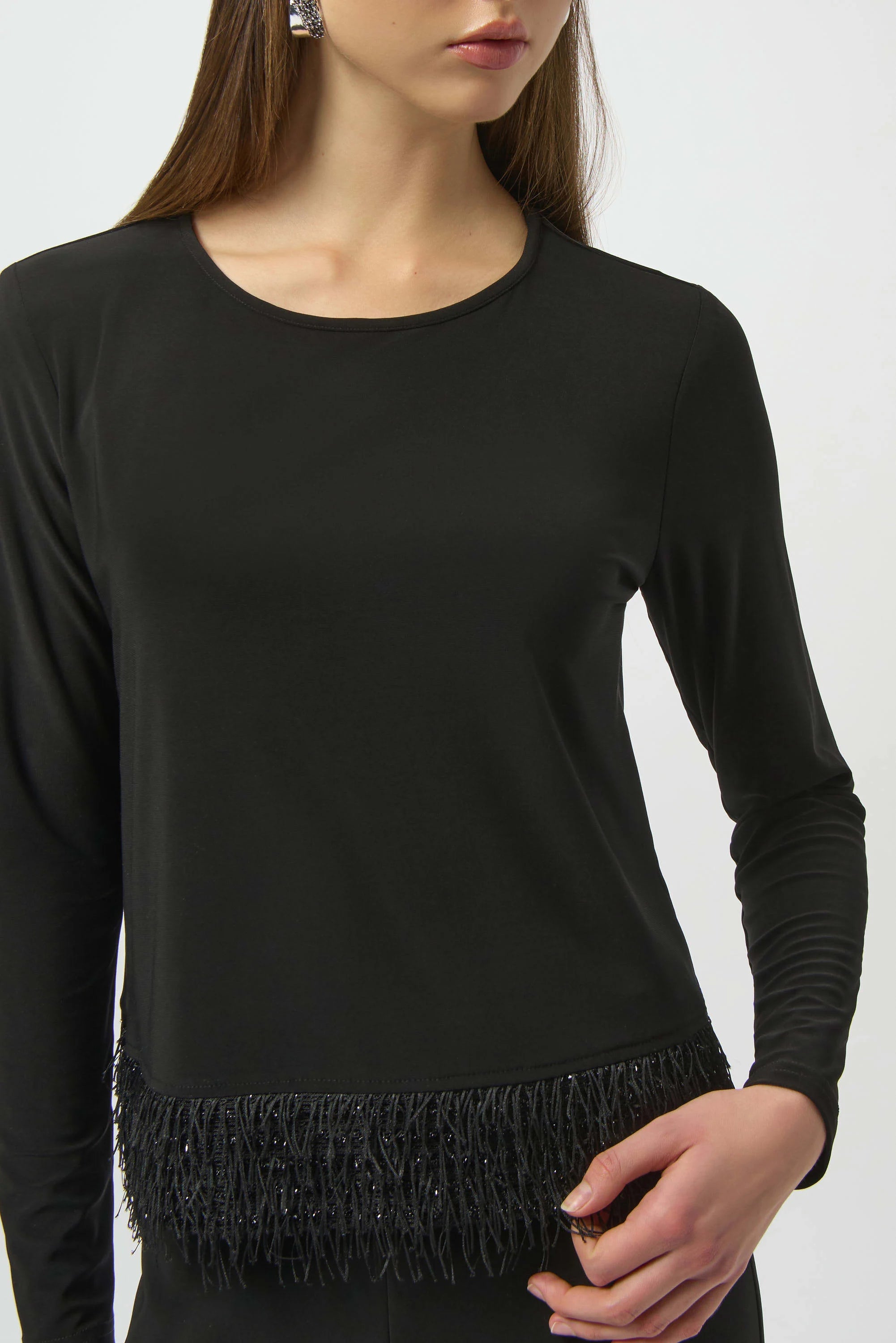 Black long-sleeve top with fringe detail on a white background