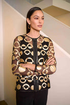 Woman wearing a black and gold patterned blouse in an indoor setting
