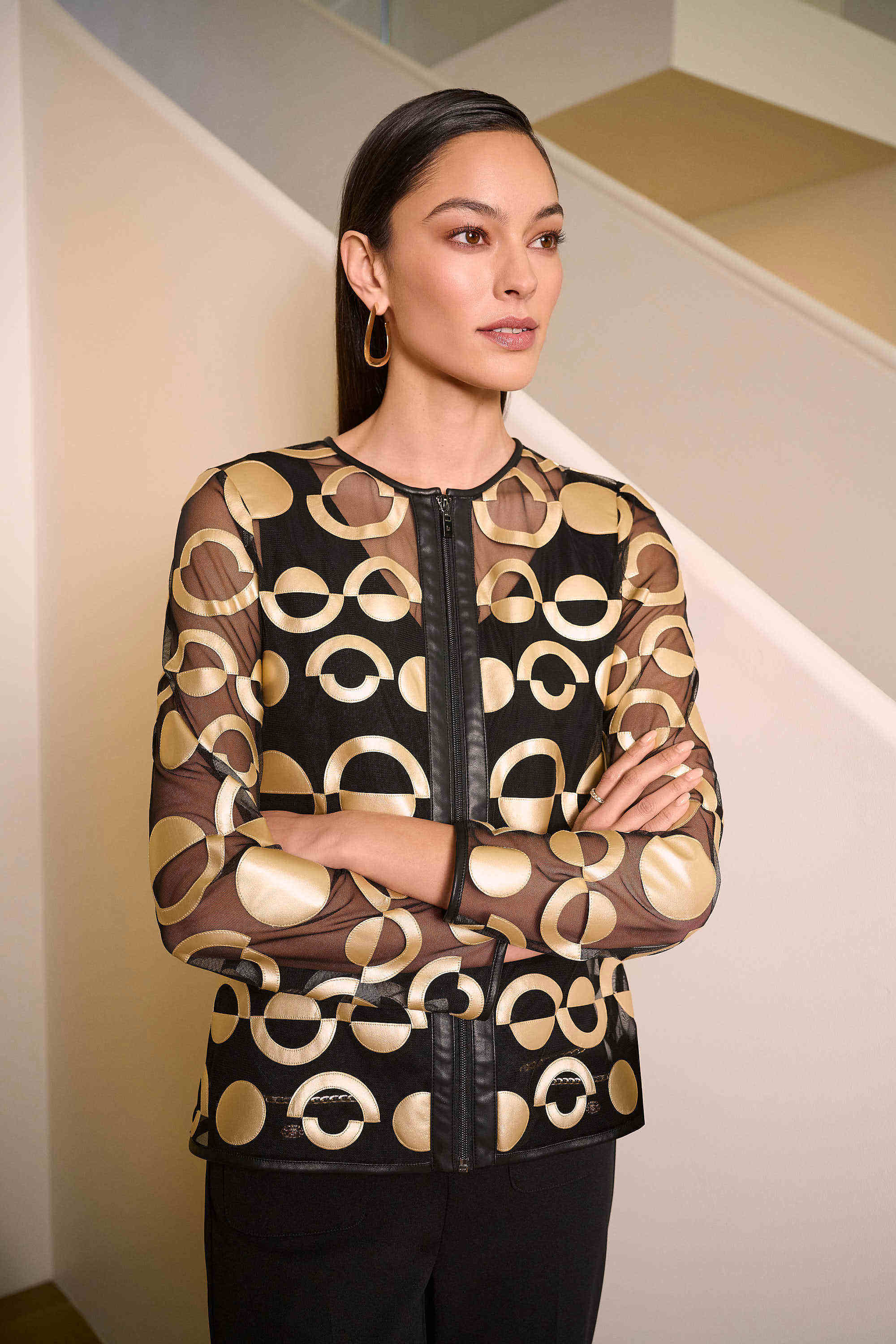 Woman wearing a black and gold patterned blouse in an indoor setting