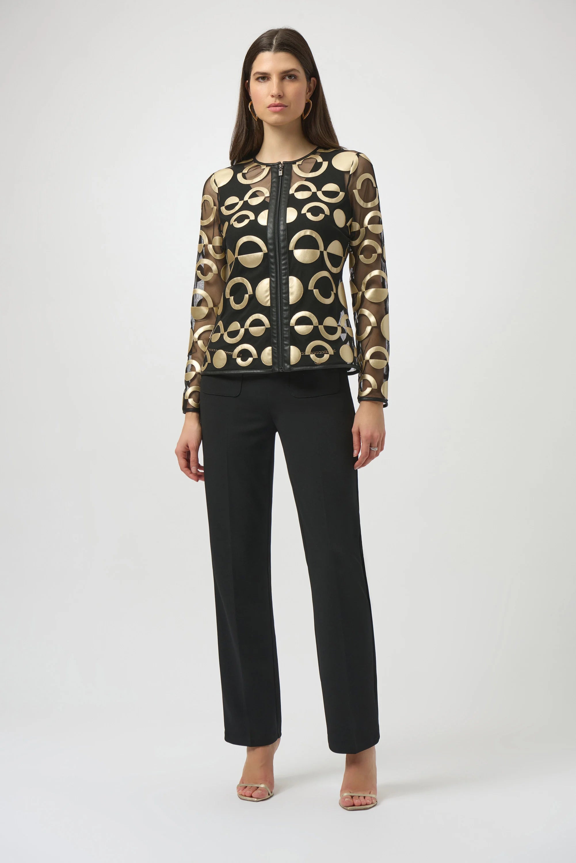 Woman wearing a patterned jacket and black pants on a white background