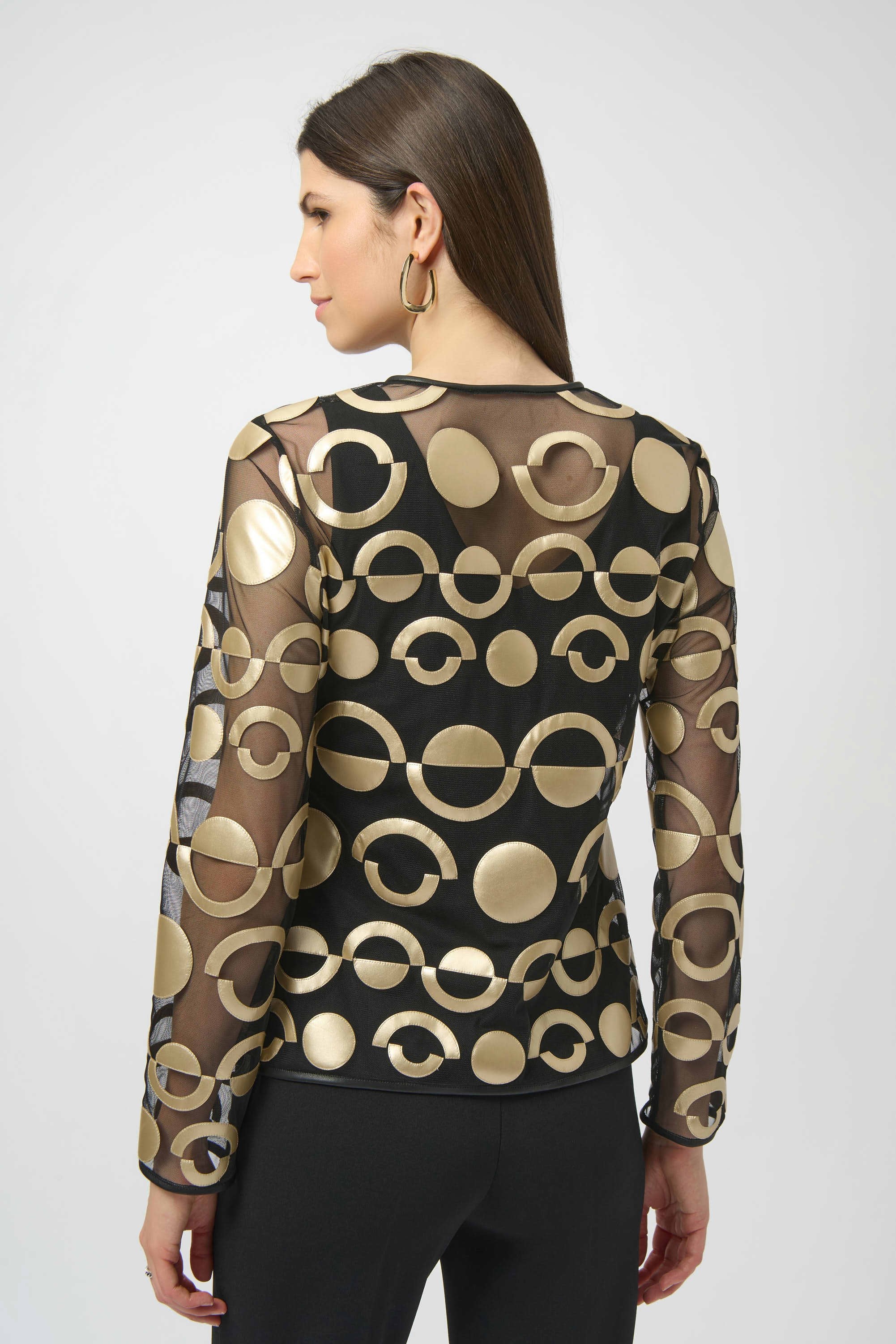 Woman wearing a black and gold patterned sheer top on a white background