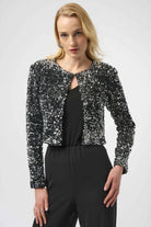Woman wearing a black sequin jacket over a black top and pants on a white background