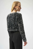 Woman wearing a black sequin top and black pants on a white background