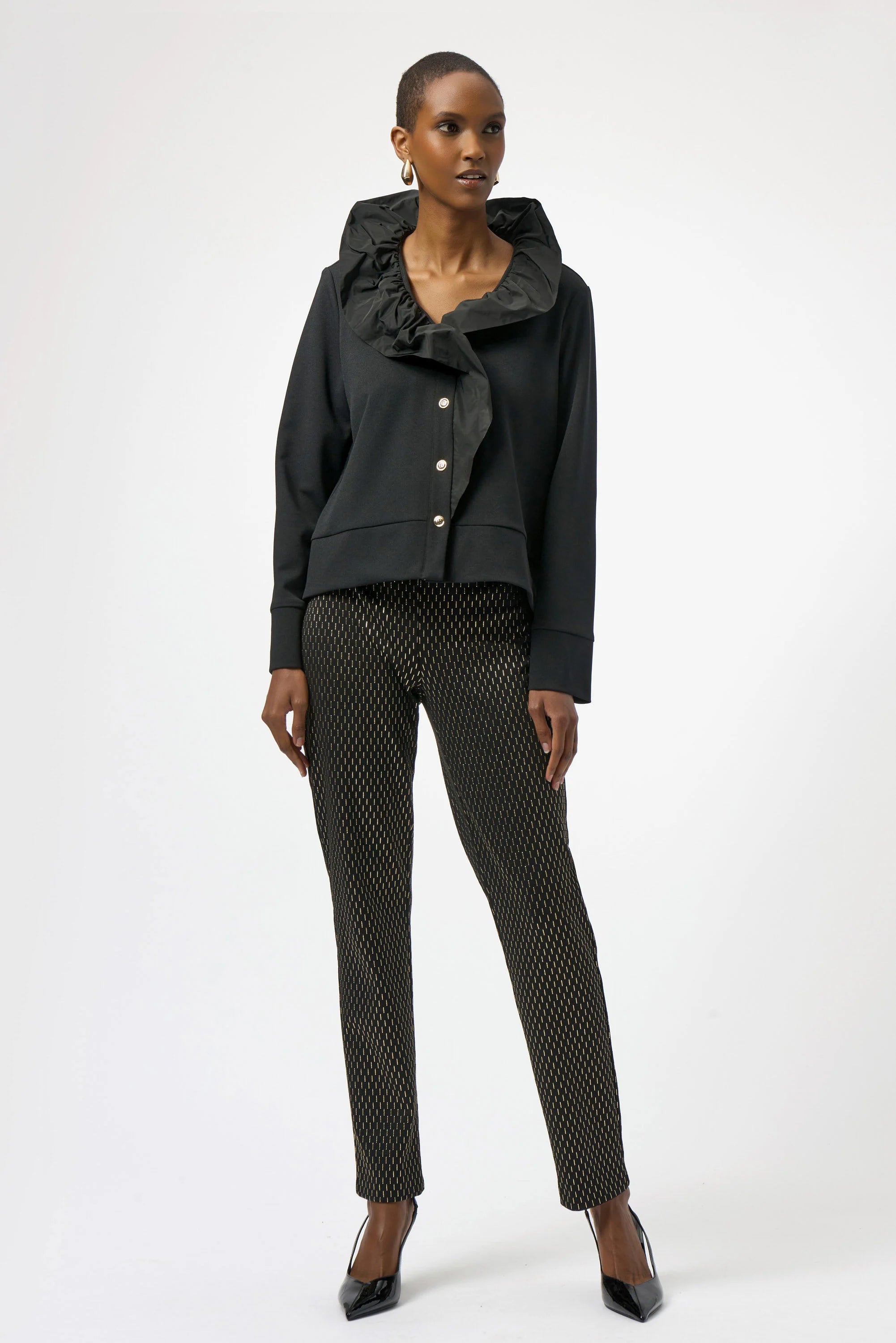 Woman wearing a black outfit with a patterned top and pants on a white background