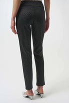 Black patterned pants worn by a person on a white background