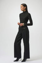 Woman wearing a black turtleneck and wide-leg pants on a white background