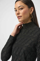 Woman wearing a black textured long-sleeve top against a white background