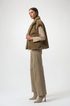 Woman wearing a brown faux fur vest and beige pants on a white background