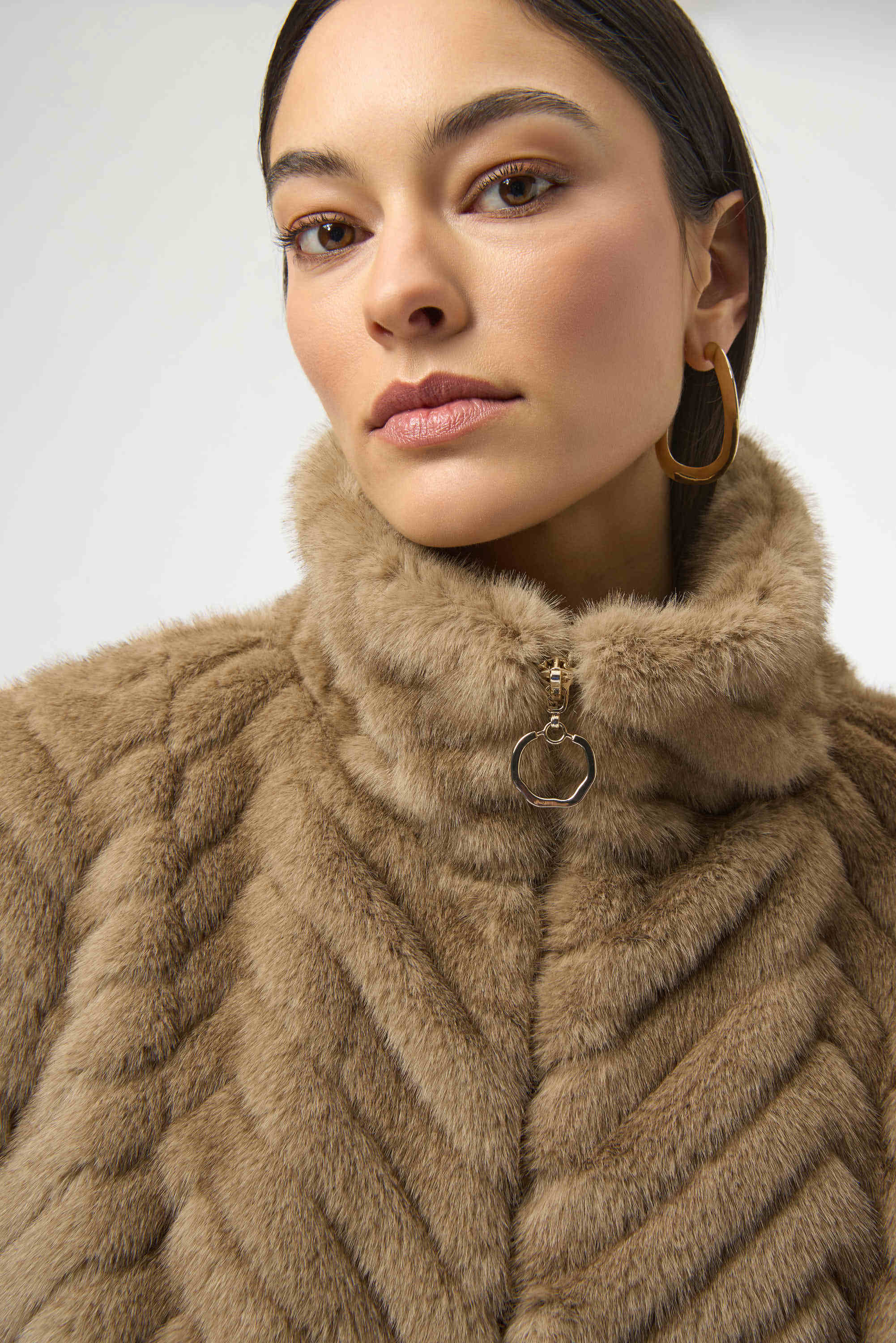Woman wearing a beige fur coat with a white background