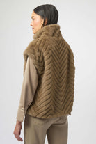 Woman wearing a brown knitted vest over a beige coat on a white background