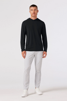 Man wearing a black long-sleeve shirt and white pants on a white background