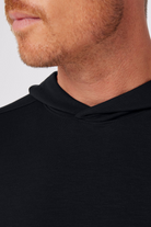 Close-up of a person wearing a black hoodie with a neutral background
