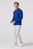 Man wearing a blue long-sleeve shirt and white pants on a white background
