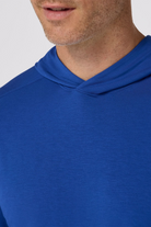 Close-up of a person wearing a blue hoodie with a plain background