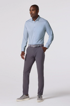 Man wearing a light blue shirt and gray pants on a white background
