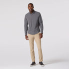 Man wearing a gray button-up shirt and beige pants on a white background