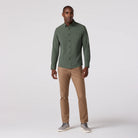 Man wearing a green shirt and beige pants on a white background