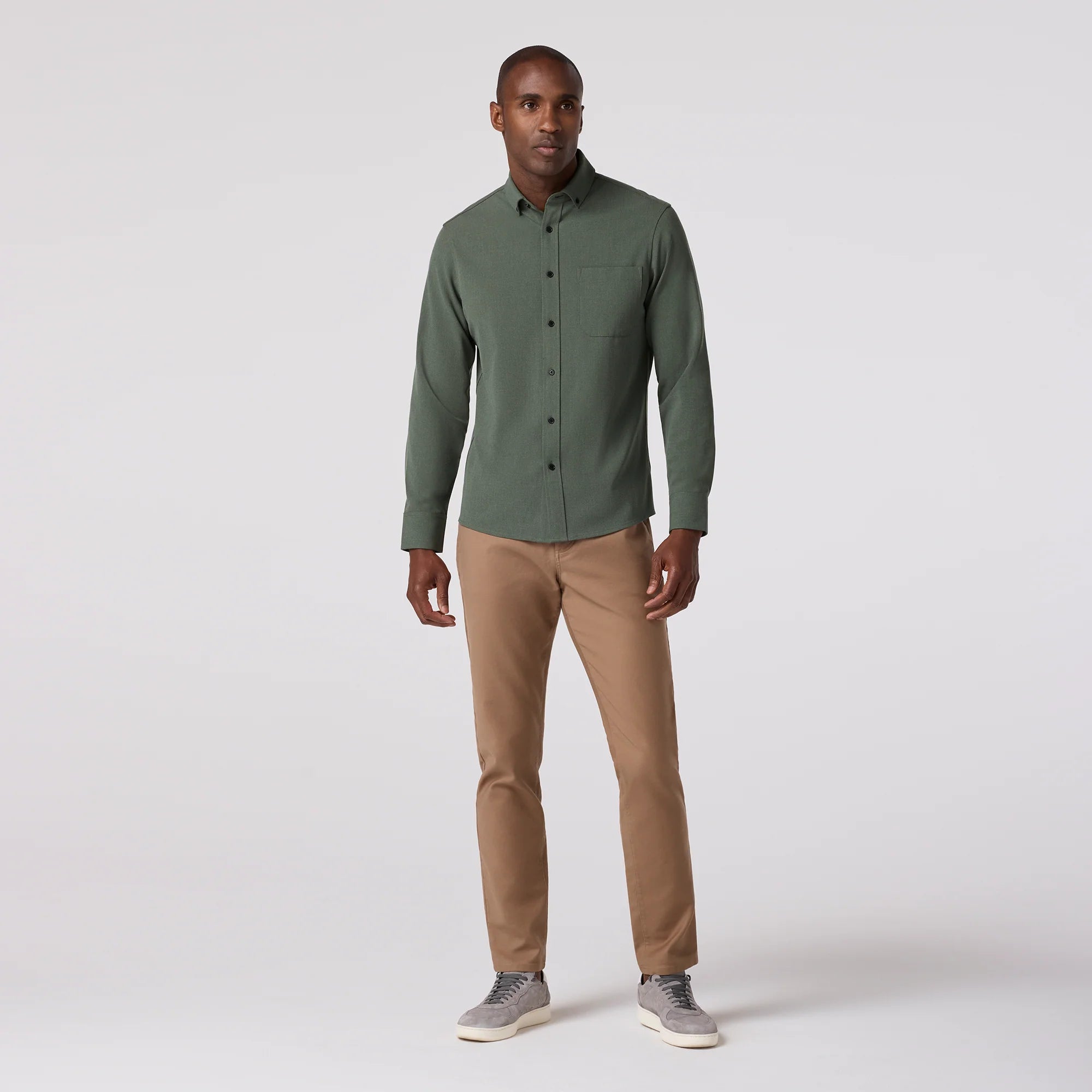 Man wearing a green shirt and beige pants on a white background