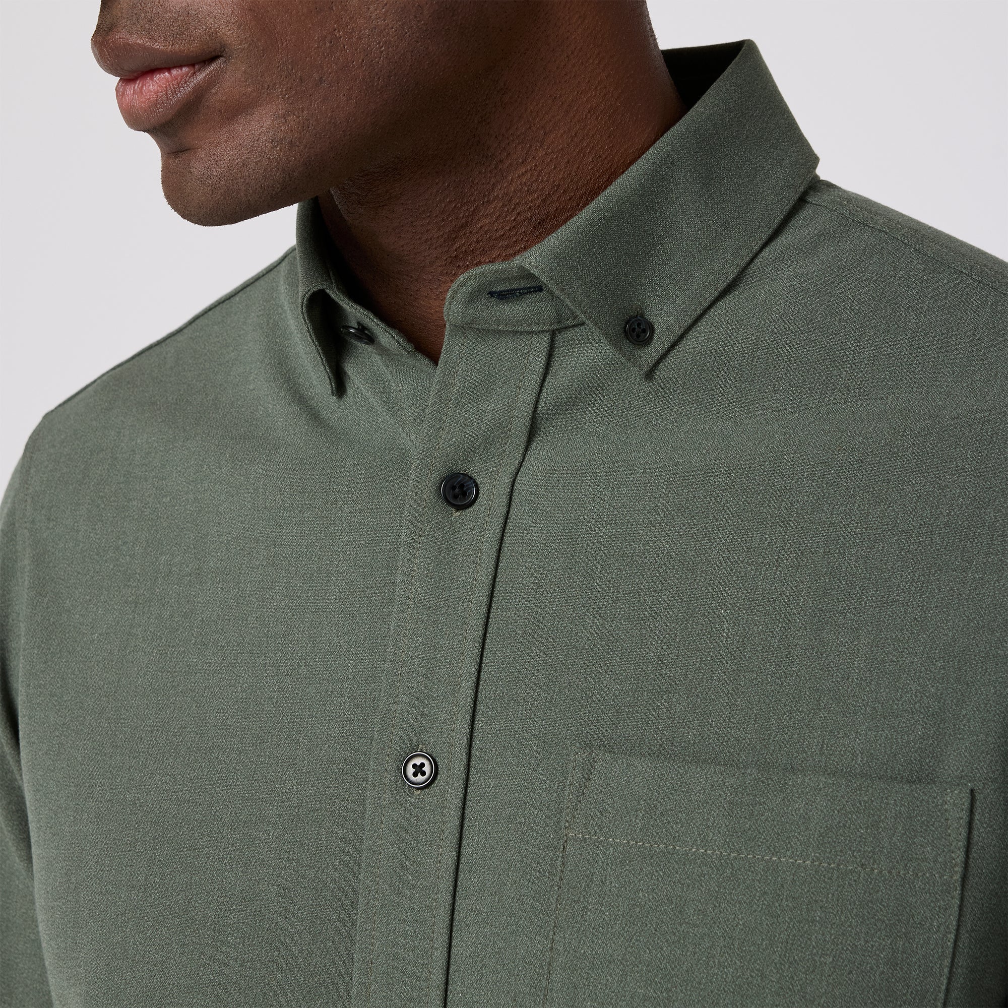 Green button-up shirt worn by a person on a plain background