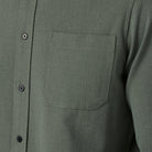 Close-up of a green button-up shirt with a pocket and buttons.