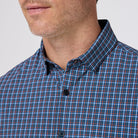 Close-up of a person wearing a blue and orange plaid shirt against a plain background