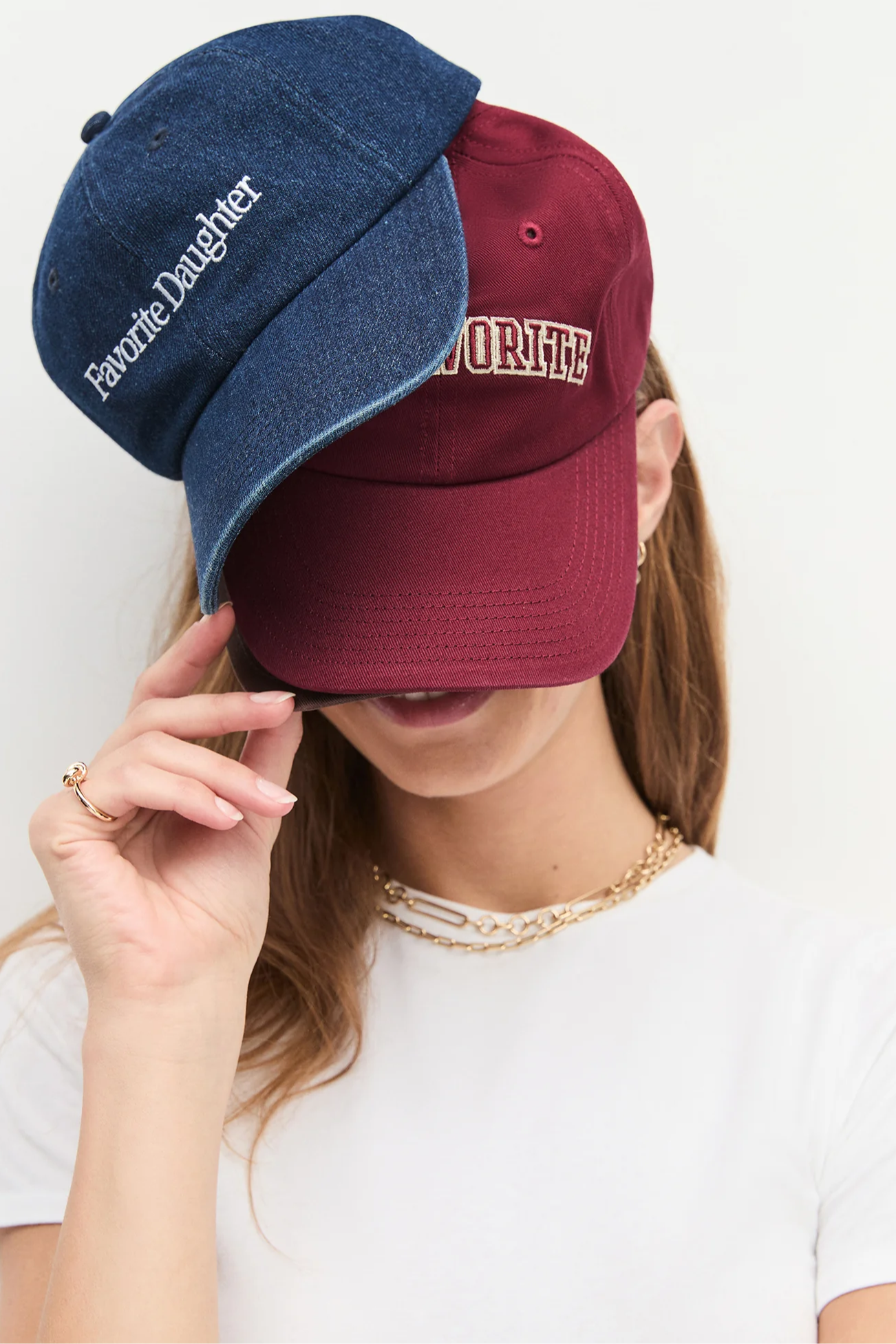 Two baseball caps, one blue and one red, worn by a person on a white background.