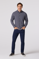 Man wearing a blue checkered shirt and navy pants on a white background