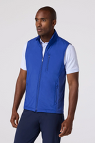 Man wearing a blue vest over a white shirt on a white background