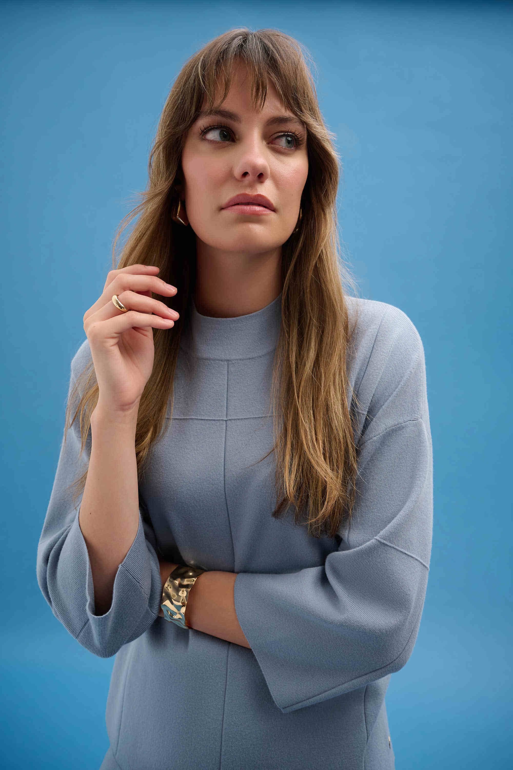 Woman wearing a light blue dress against a blue background