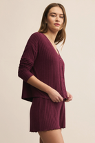 Woman wearing a maroon ribbed outfit on a beige background