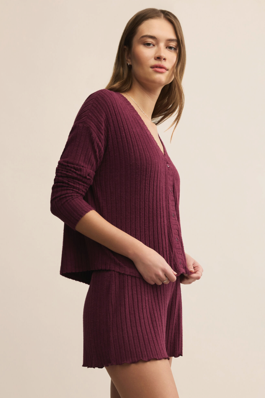 Woman wearing a maroon ribbed outfit on a beige background