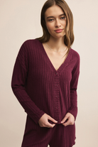 Woman wearing a burgundy ribbed cardigan on a beige background