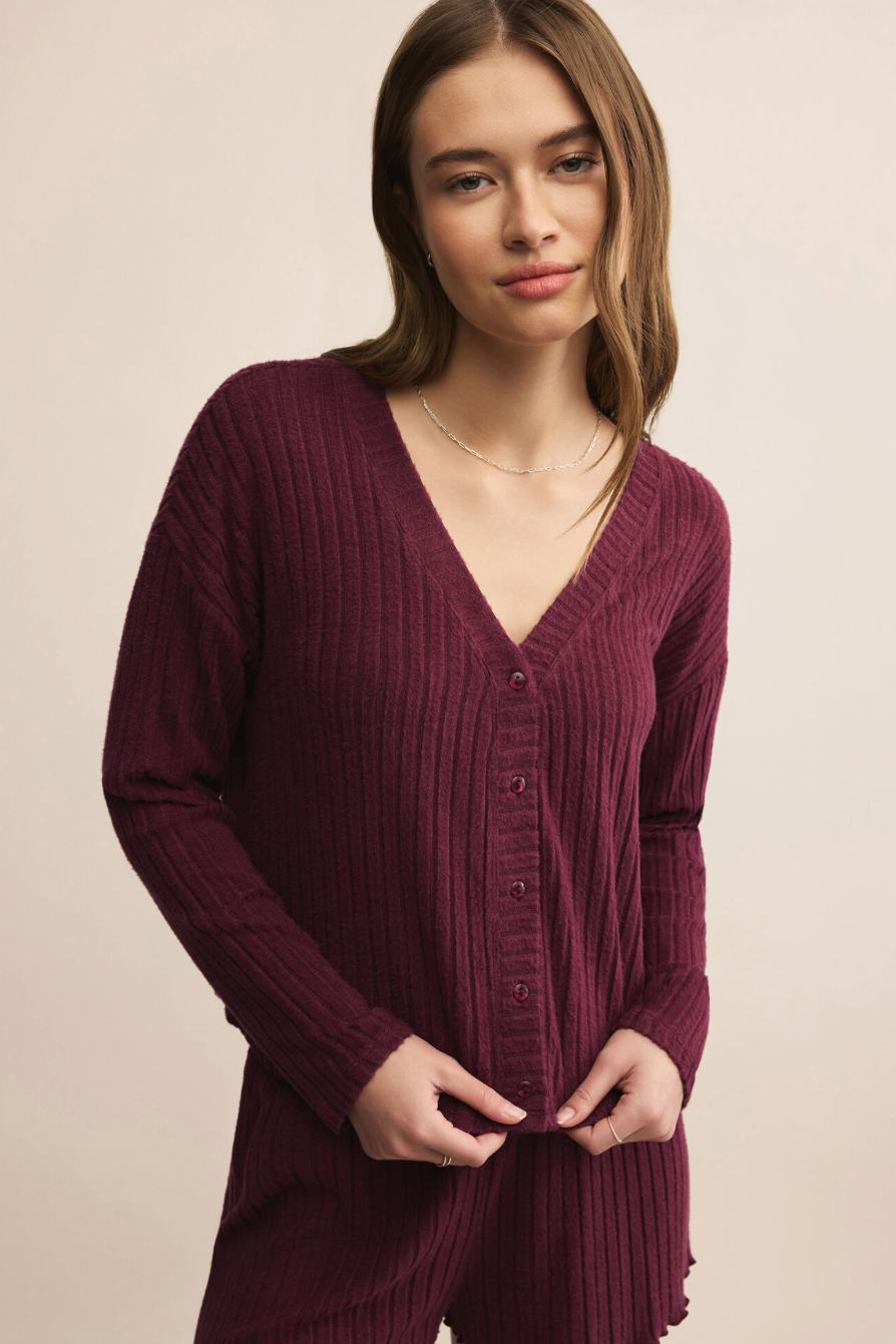 Woman wearing a burgundy ribbed cardigan on a beige background