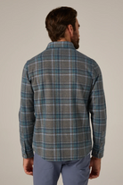 Man wearing a plaid shirt and pants against a plain background