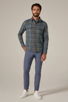 Man wearing a plaid shirt and blue pants on a beige background