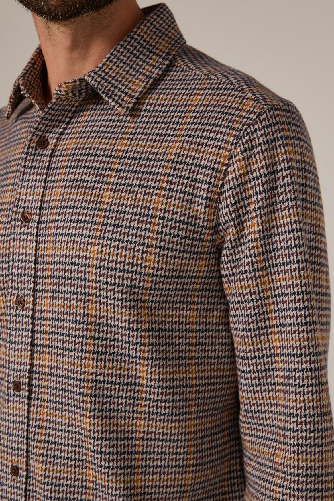 Houndstooth patterned shirt worn by a person on a neutral background