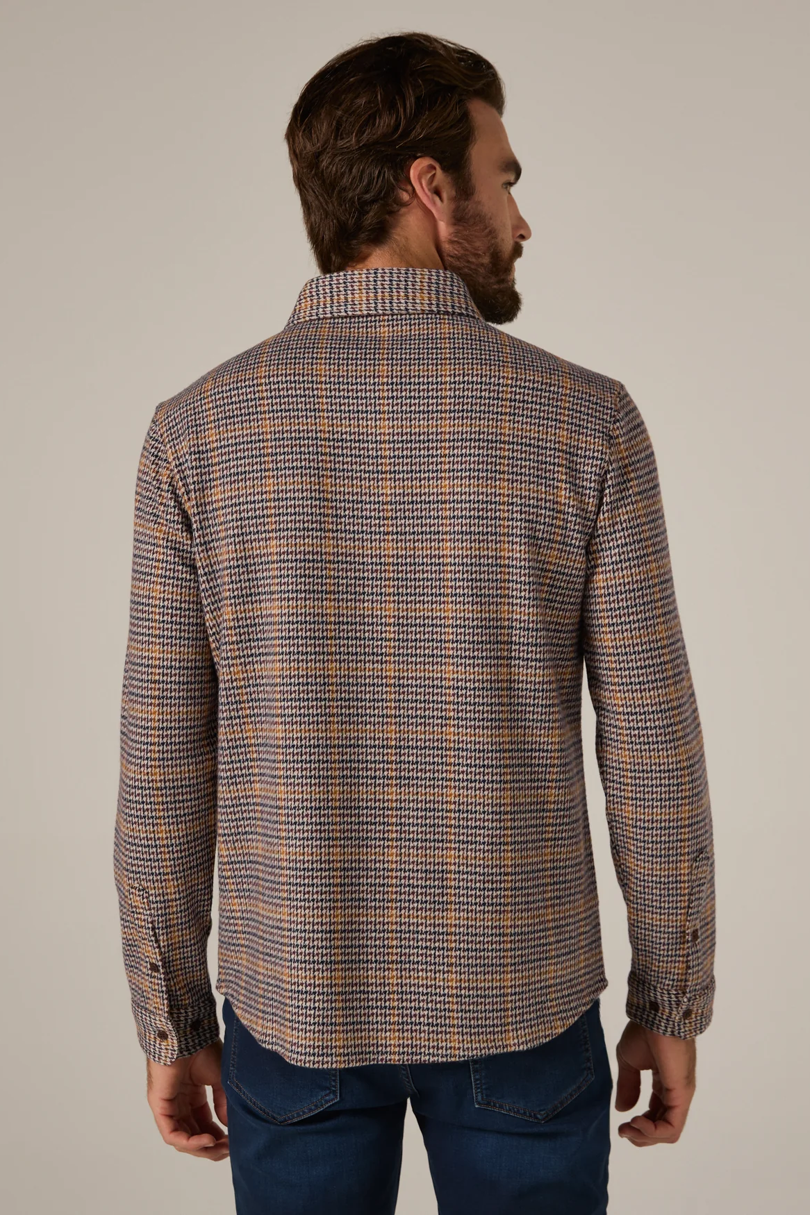 Man wearing a plaid shirt with a neutral background