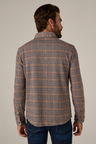 Man wearing a plaid shirt with a neutral background
