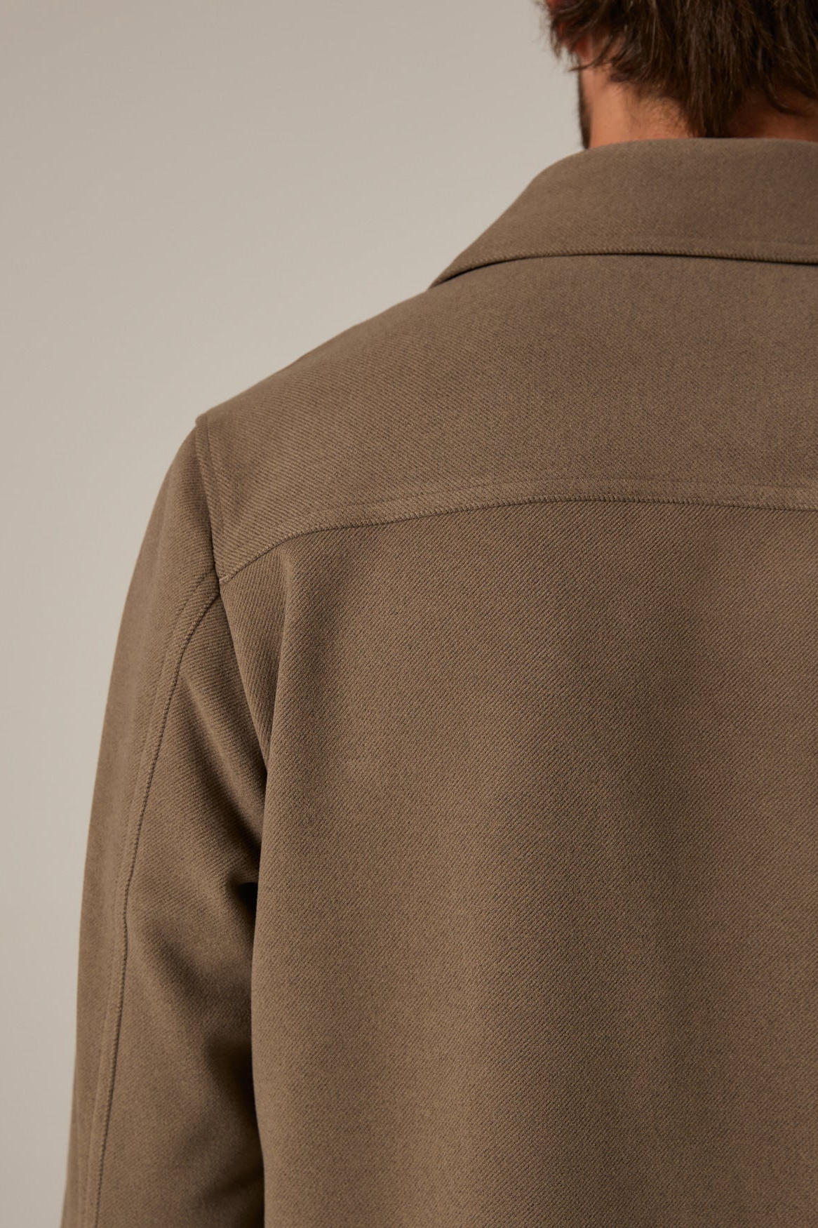 Brown jacket worn by a person on a plain background