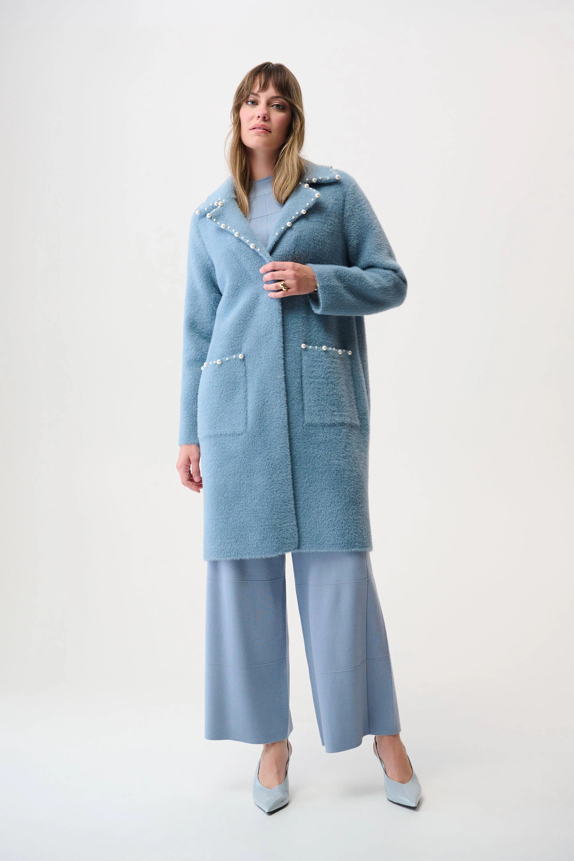 Woman wearing a light blue coat and pants on a white background